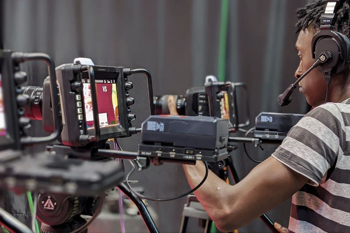 Camera operator adjusting equipment during a live video production, symbolizing professional broadcasting and video creation.