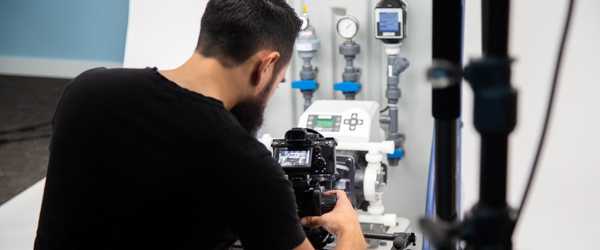 Alexis Mendez from Coldea Productions films a Plastic Chemical Feed Skid, capturing detailed shots for a product video using professional video equipment.