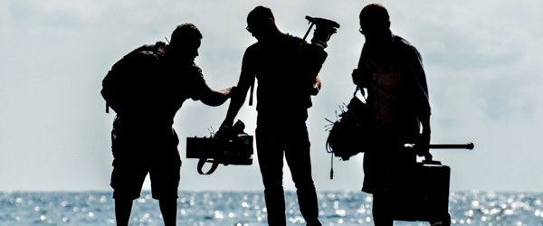 Silhouetted film crew working outdoors by the ocean, ideal for production companies in Arizona, by Coldea Productions.