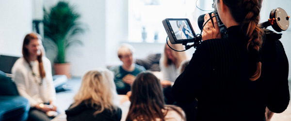 Videographer filming a group discussion in a casual setting, ideal for company culture and team video production.