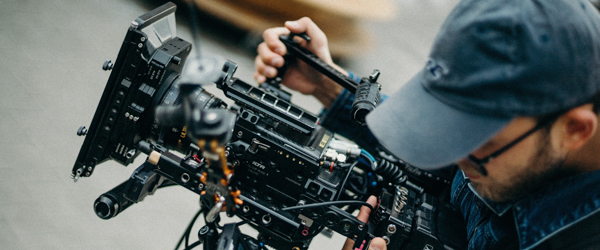 A focused cinematographer adjusts a high-end professional camera during a video production shoot.