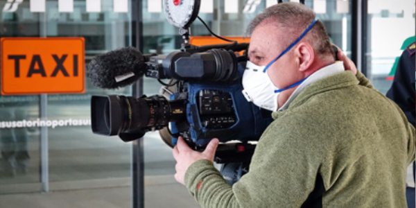 Cameraman using a professional camcorder outdoor filming news while wearing mask prevent Covid-19 or coronavirus quarantine pandemic.