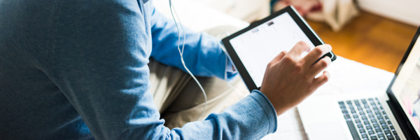 A person using a tablet and laptop for financial services video marketing, captured by Coldea Productions in Los Angeles.